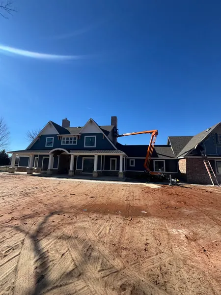 painting crew using a boom lift to paint a two story home exterior near Oklahoma City